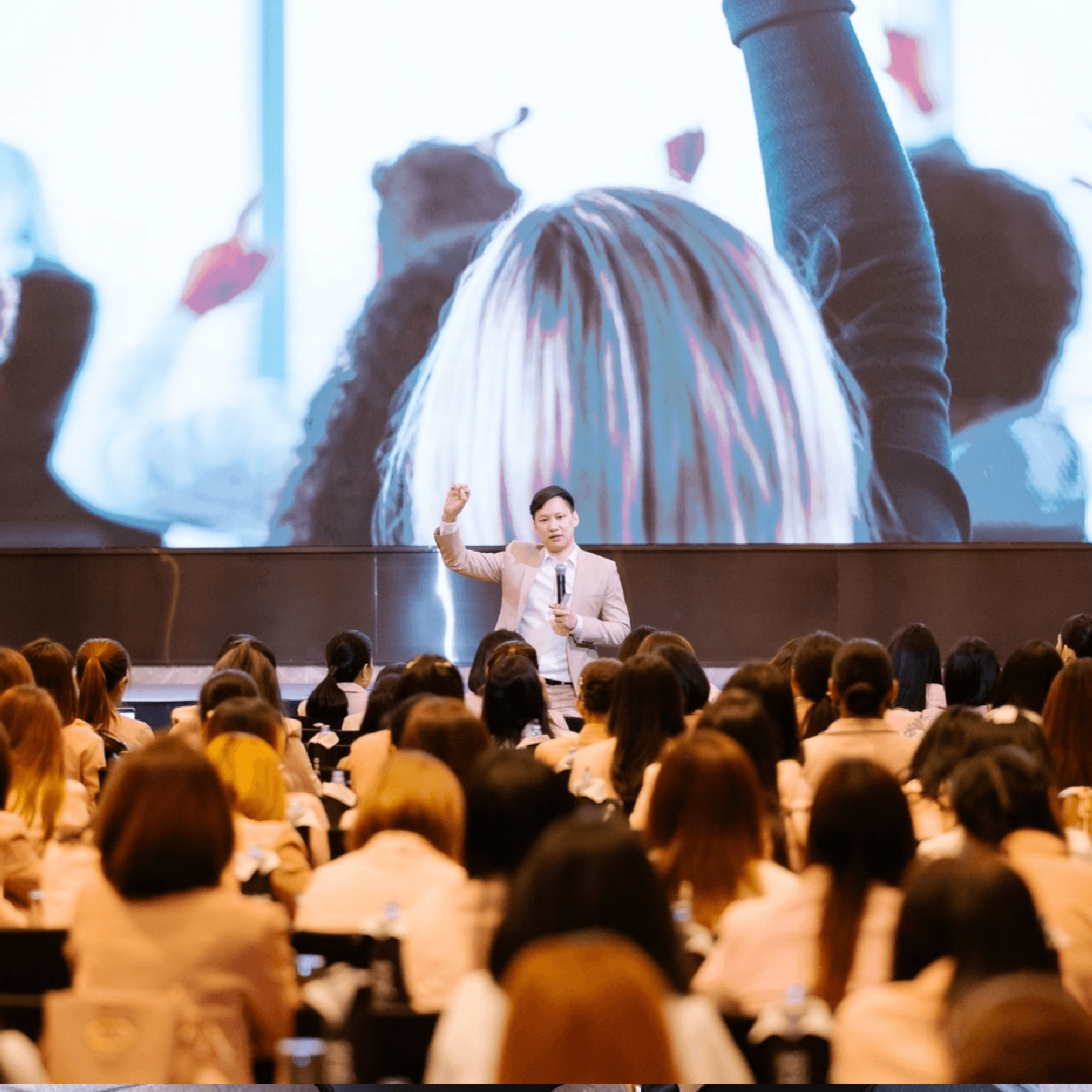 สอนบนเวที กำมือชูขึ้น ผู้เข้าร่วมเต็มห้อง